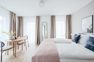 a white bedroom with a large bed and a table at limehome Metzingen Wilhelmstr in Metzingen