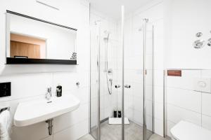 a white bathroom with a sink and a shower at limehome Metzingen Wilhelmstr in Metzingen