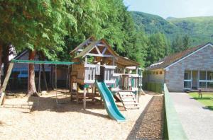 une aire de jeux avec une maison et un toboggan dans l'établissement Loch Awe Holiday Park, à Taynuilt