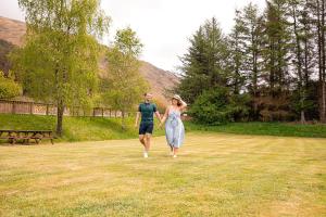 a man and a woman walking through a field at Loch Awe Holiday Park in Taynuilt