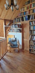 Zimmer mit Bücherregalen und einem Stuhl im Dachgeschoss in der Unterkunft Mājīga istaba ar balkonu un vannasistaba, bezmaksas elektroauto uzlāde in Iecava