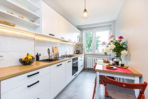 uma cozinha com armários brancos e uma mesa com um vaso de flores em Serene Apartment in the City Center em Cracóvia