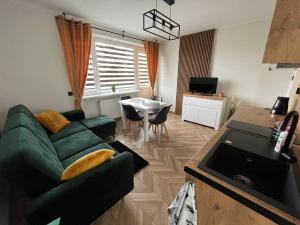 a living room with a green couch and a table at Pensjonat u Tosiek in Stegna