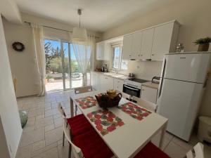 uma cozinha com uma mesa e um frigorífico branco em Amalia's Summer Home em Áyioi Asómatoi