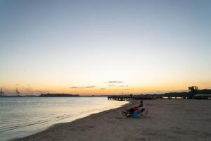 a man sitting on a chair on the beach at sunset at Villa Gumio 2BR Apt- 7 min walk to Boca Chica Beach apts in Boca Chica