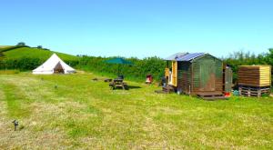 a field with a tent and a table and a teepee at Ffos Wilkin Glamping & Alpacas in Kidwelly