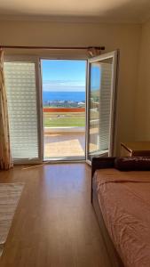ein Zimmer mit einem Bett und einer großen Glasschiebetür in der Unterkunft casa panorâmica bela vista in Angra do Heroísmo