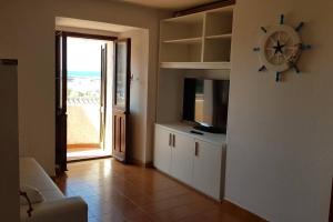 a living room with a clock on the wall and a television at Appartamento vista mare Buggerru in Buggerru