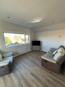 sala de estar con sofá y TV de pantalla plana en Lake District Coastal cottage, en Seascale