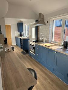 a large kitchen with blue cabinets and a wooden floor at Lake District Coastal cottage in Seascale