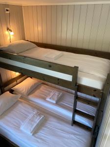 two bunk beds in a room with white sheets at Fjordly Ungdomssenter in Bryggja