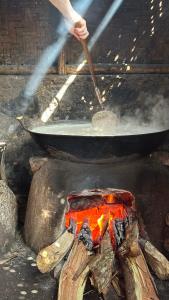 une personne qui cuisine de la nourriture dans un bac au-dessus d'un feu dans l'établissement Jonny's Places, à Tetebatu