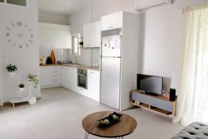 eine weiße Küche mit einem Tisch und einem Kühlschrank in der Unterkunft Cosy apartment 700m from Acropolis in Athen