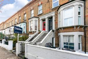 een bord voor een bakstenen gebouw met een rode deur bij Stunning Modern two bedroom flat near Notting hill Gate in Londen