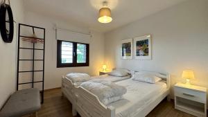 sypialnia z 2 łóżkami z białą pościelą i oknem w obiekcie Anastasias Cottage w mieście Nea Iraklia