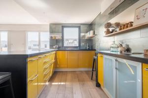 a large kitchen with yellow cabinets and wooden floors at City Escape in Le Bourget