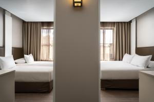 two beds in a room with two windows at Protea Hotel by Marriott Cape Town Waterfront Breakwater Lodge in Cape Town