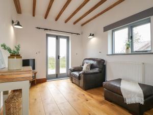 sala de estar con sillón de cuero y sofá en Postbox Cottage en Ashbourne