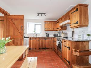 cocina con armarios de madera y encimera en Postbox Cottage en Ashbourne