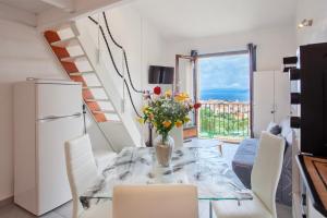 une salle à manger avec une table avec un vase de fleurs dans l'établissement San Lucianu - Appt vue mer et montagne, à LʼÎle-Rousse