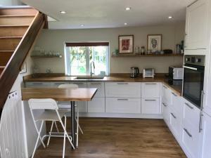 una cucina con armadi bianchi e tavolo in legno di Charming modernized country cottage Near Mere, Wiltshire a Mere