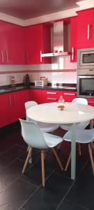 a kitchen with red cabinets and a white table and chairs at Casa Pepe in Meaño +14 photos