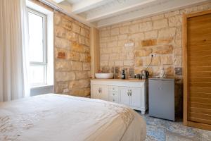 a bedroom with a bed and a stone wall at Via Maria Boutique Suites In The Middle Of The city in Haifa