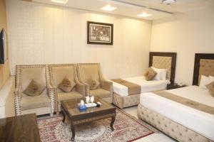 ein Hotelzimmer mit 2 Betten, einem Sofa und einem Tisch in der Unterkunft Park View Hotel Gulberg in Lahore