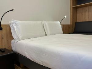 uma cama branca com duas almofadas em cima em YUGOGO MAZZINI 41 - BILOCALE Trento Centro em Trento