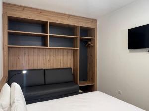 a bedroom with a black couch and a tv at YUGOGO MAZZINI 41 - BILOCALE Trento Centro in Trento
