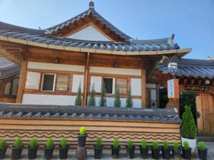 a house with a chinese roof and potted plants at Beautiful House in Jeonju