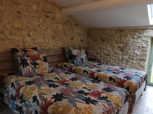 a bedroom with two beds and a stone wall at Maison de village ancienne poste in Bourdic