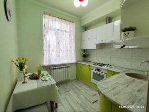 a kitchen with yellow and white cabinets and a window at Стильный уют в центре in Almaty