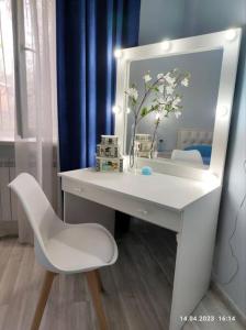 een wit bureau met een spiegel en een witte stoel bij Стильный уют в центре in Alma-Ata