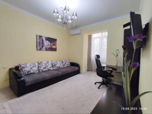 a living room with a black couch and a desk at Стильный уют в центре in Almaty