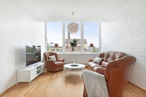 sala de estar con 2 sillas de cuero y mesa en Guestly Homes - 3BR City Charm en Piteå