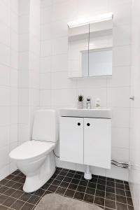 a white bathroom with a toilet and a sink at Guestly Homes - 3BR City Charm in Piteå