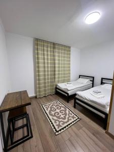 um quarto com duas camas e uma mesa e um tapete em Kezgin Guest House em Naryn