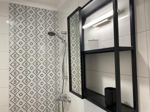 uma casa de banho com um chuveiro, um espelho e uma prateleira em Студио Ирма em Burgas