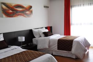 a bedroom with two beds and a painting on the wall at Amérian Villa Maria Park Hotel in Villa María