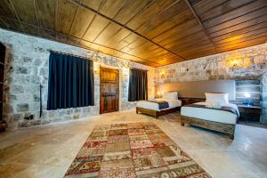 a bedroom with two beds and a stone wall at Cappadocia Hobbit House in Nevşehir