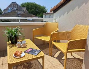 dwa krzesła i stół z talerzem jedzenia na balkonie w obiekcie Appart'City Confort Niort Centre w mieście Niort