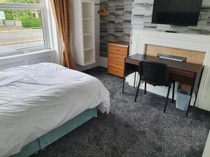 Schlafzimmer mit einem Bett, einem Schreibtisch und einem TV in der Unterkunft Lyndene House in Huddersfield