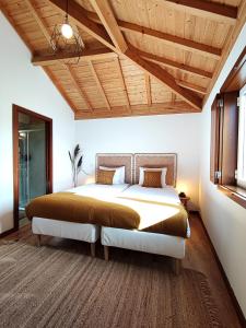 Couto的住宿－Verde Água Agroturismo e Agricultura Biológica，一间卧室设有一张大床和木制天花板