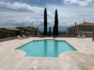 a swimming pool in front of a house with trees at Fattoria Colsanto in Torre del Colle