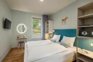 a bedroom with a large white bed and a window at Center Parcs Eifel Mosel Nürburgring in Gunderath