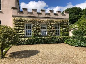 un edificio cubierto de hiedra con ventanas y un patio en The West Wing - Bride Valley - Jurassic Coast en Long Bredy