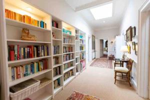 a library with white shelves filled with books at The West Wing - Bride Valley - Jurassic Coast in Long Bredy