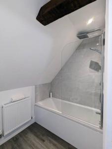 uma casa de banho branca com uma banheira e uma cabina de duche em vidro. em The Livery Cottage at Cefn Tilla Court, Usk em Usk