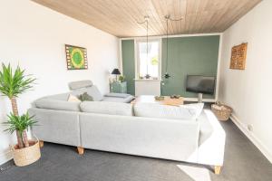 sala de estar con sofá blanco y TV en Parkvejens feriebolig en Bindslev